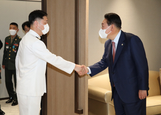 윤석열 대통령이 9일 서울 용산 대통령실 청사에서 열린 '호국영웅 초청 소통식탁' 행사에 앞서 제2연평해전 생존자인 이희완 중령과 인사하고 있다. 대통령실통신사진기자단=연합뉴스